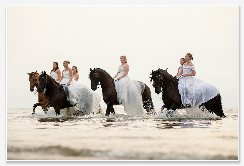 Bruiden te paard op het strand van Noordwijk