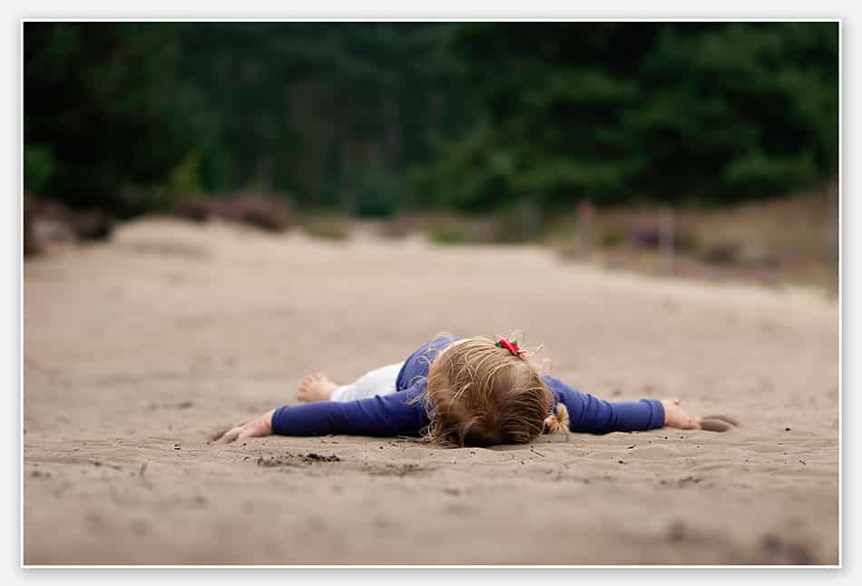 Kind ligt uitgeteld op het zand
