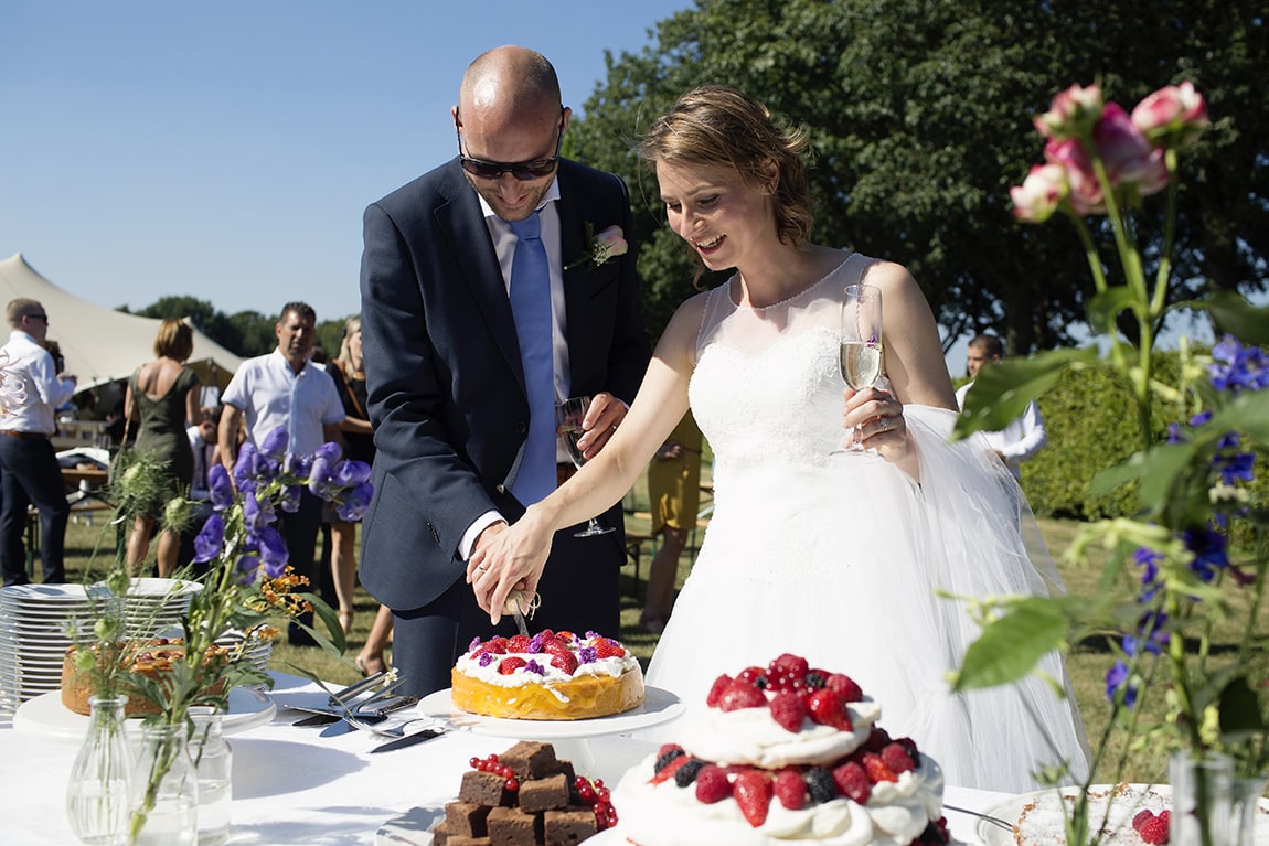 Bruidspaar snijd taart aan bij bruiloft in Vinkel