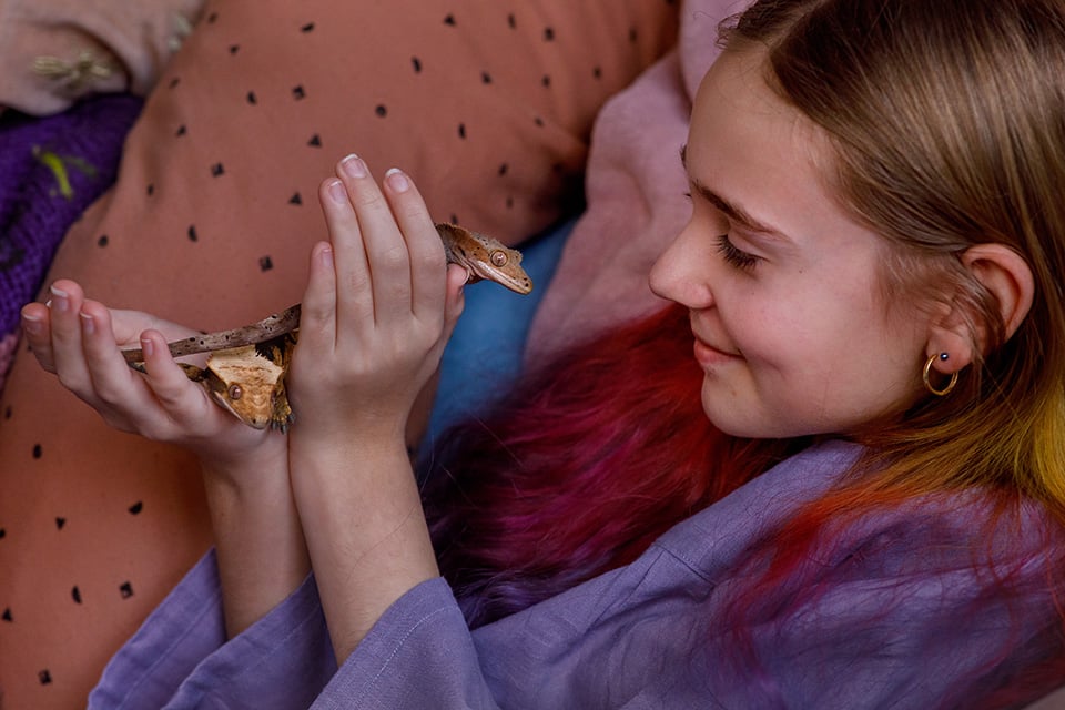 Meisje glimlacht naar twee gekko's in haar hand