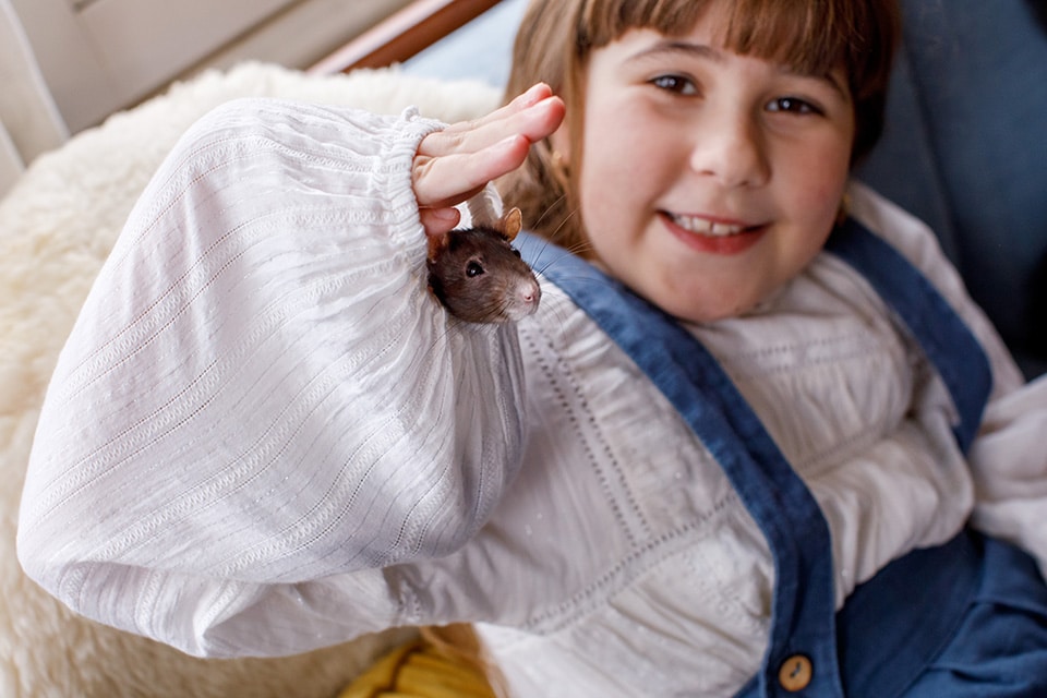 Meisje lacht naar haar ratje dat uit de mouw van haar witte blouse kijkt