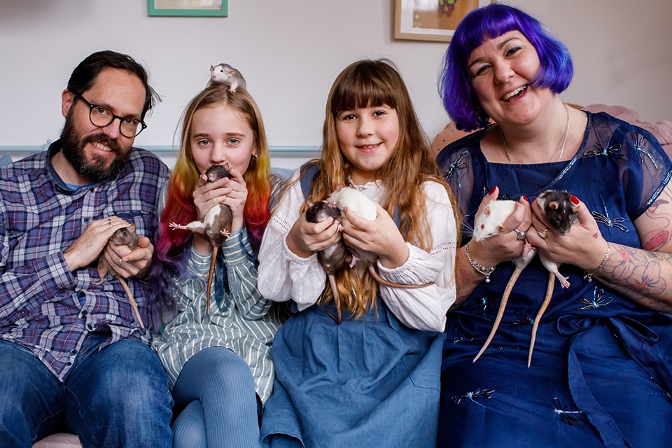 Ouders en twee dochters zitten vrolijk met hun 7 ratje op de bank bij Familiefotografie  Amsterdam